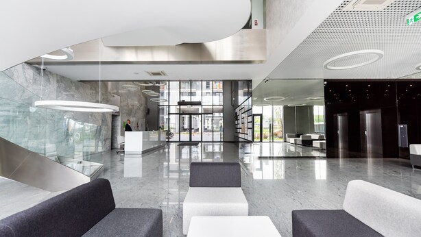 A modern lobby with a glass wall, seating areas, and a reception desk. - Wola Chic Luxury Studio (Warszawa)
