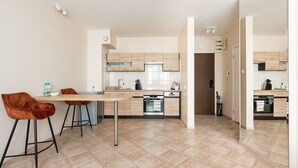 Een moderne keuken met een centraal eiland, twee barkrukken en een eettafel.