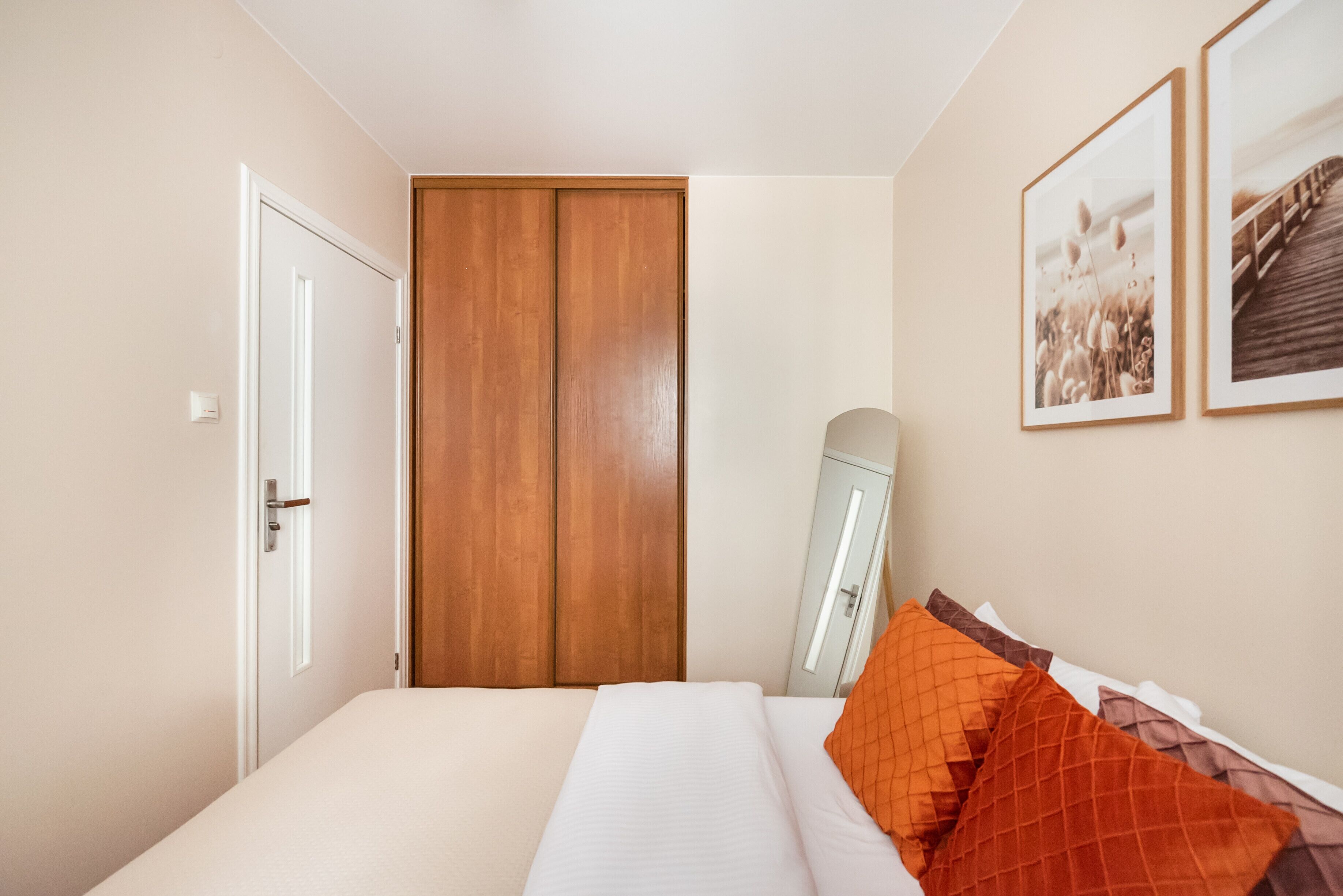 Ein Schlafzimmer mit einem Bett, einem Holzschrank und zwei gerahmten Bildern an der Wand.