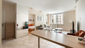 Een moderne hotelkamer met een zithoek, een bank, een televisie en uitzicht op de stad.