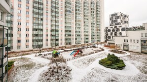 Een hoog appartementencomplex met meerdere balkons en een speelruimte met glijbanen en speeltoestellen.