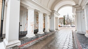 Un paseo techado con columnas blancas y suelo de baldosas.