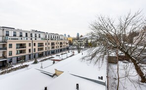 Un immeuble résidentiel à plusieurs étages, doté de balcons et dont le sol est recouvert de neige.