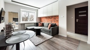 Una sala moderna con un sofá gris, una mesa de centro redonda y una pared de ladrillo decorativa.