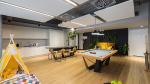 A modern kitchen with white cabinets, a dining table, and a pool table. - Business Park Blue Studio (Warszawa)