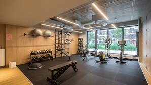 A modern gym with various exercise equipment, large windows, and a wooden interior. - Business Park Blue Studio (Warszawa)
