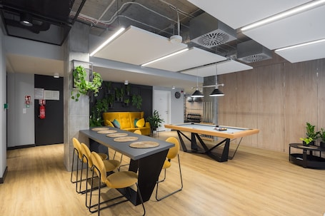 A modern meeting room with a long table, yellow chairs, and a pool table.