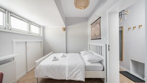 A bedroom with a bed, white wardrobe, and a hanging light fixture.
