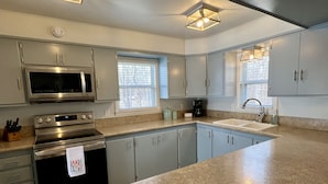 A modern kitchen with stainless steel appliances, a granite countertop, and a large island. - Home in Disney - Ride Directly to Trails, 1/2 mile to Marina & Boat Ramp (Disney)