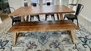 A dining area with a wooden table and benches, a patterned rug, and a chandelier. - Home in Disney - Ride Directly to Trails, 1/2 mile to Marina & Boat Ramp (Disney)