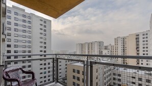 A balcony with a view of high-rise buildings, a metal railing, and a plastic chair. - Metro Bemowo Comfort Studio (Warszawa)