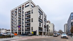 A modern multi-story building with balconies, a parking area, and a clear sky. - Metro Wierzbno Cosy Apartment (Warszawa)