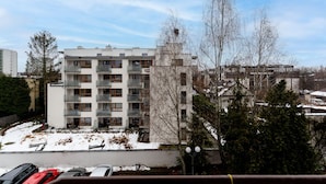 Ein mehrstöckiges Wohngebäude mit Balkonen, einem Parkplatz mit Autos und Schnee auf dem Boden.