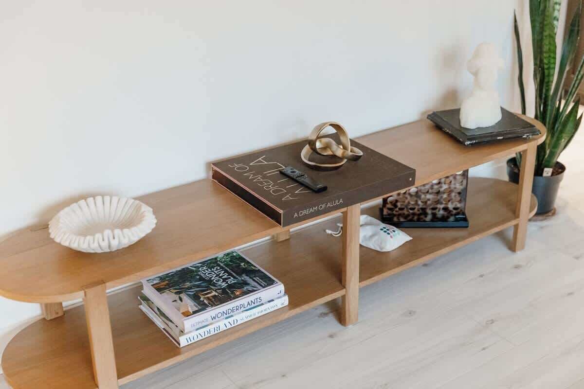 Een houten console tafel met een boek getiteld 'A Dream of Alula', een ring en een sculptuur.