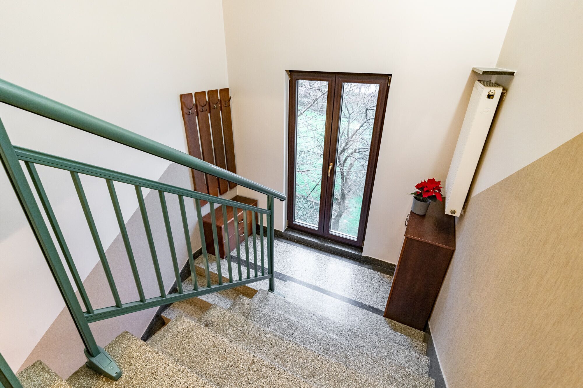 A staircase with a green metal railing leading to a landing.