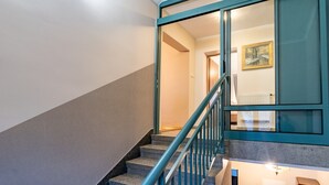 Escada com corrimãos verde-água e vista para um quarto com um quadro.