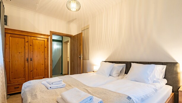 Quarto de hotel com uma cama grande, guarda-roupa de madeira e um espelho.