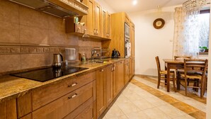 Cozinha com armários de madeira, fogão e área de jantar com mesa e cadeiras.
