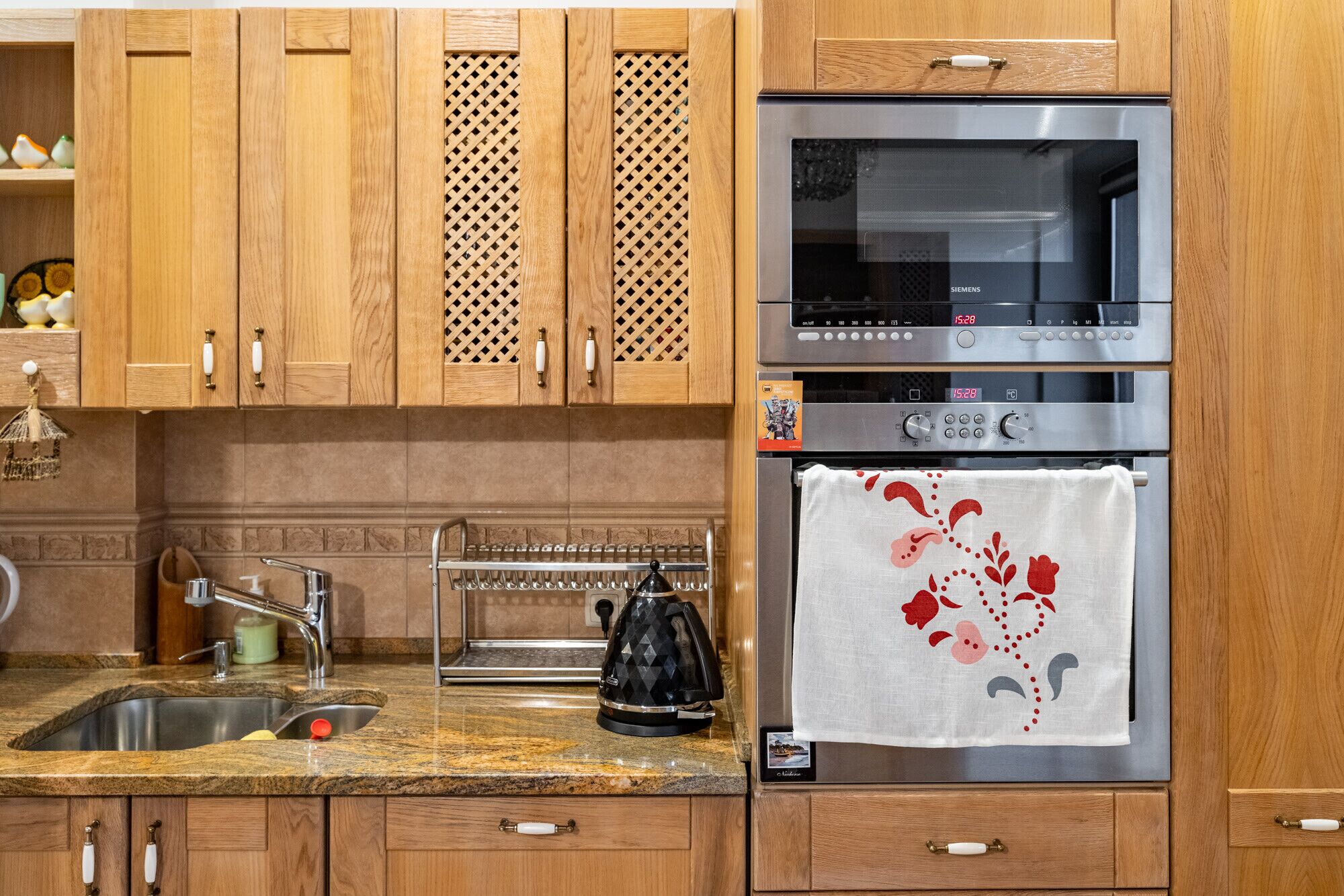 A kitchen with wooden cabinets, a stainless steel oven, a microwave, and a kettle.