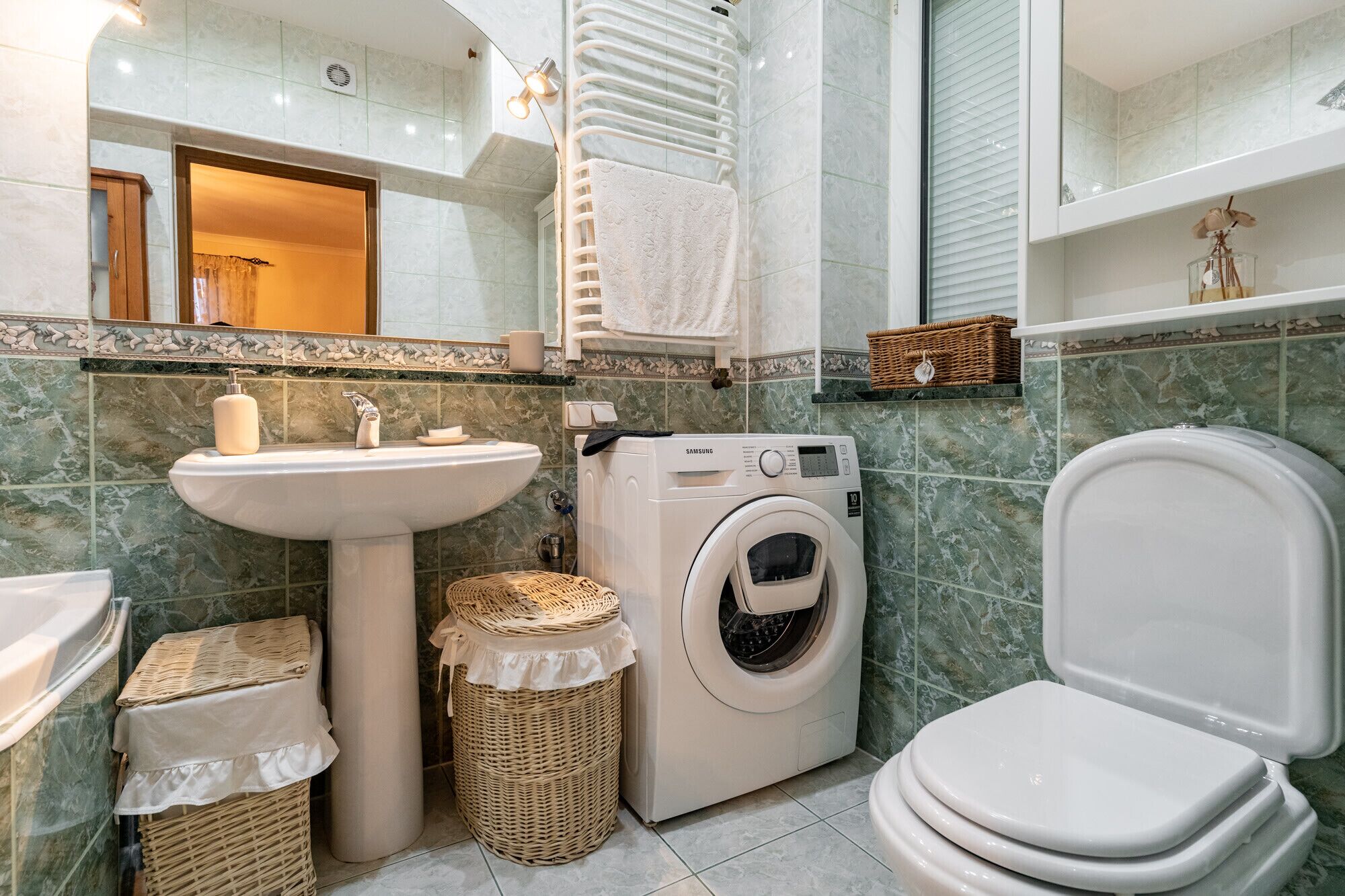 A bathroom with a sink, washing machine, and toilet.