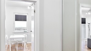 A modern interior with a white dining area, a sliding glass door, and a view of the cityscape. - 10th Floor Unii Lubelskiej Apartment (Poznań)
