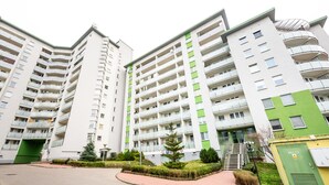 A modern apartment building with multiple balconies, a green entrance, and a parking area. - Ceramiczna Comfort Studio (Warszawa)