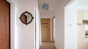 Un pasillo con una puerta de madera, un espejo y una lámpara.