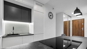 Een moderne keuken met een zwart aanrecht, witte kasten, een ingebouwde kookplaat en een klok aan de muur.