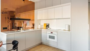 Uma cozinha moderna com armários brancos, forno embutido e cafeteira.