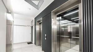 En moderne elevator med metalfinish, digitalt display og tallet '107' på væggen.
