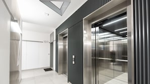 A modern elevator with a metallic finish, a digital display, and a number "107" on the wall.