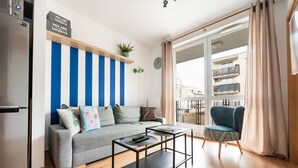 A modern living room with a grey sofa, a black coffee table, and a blue-striped wall. - Daniszewska Cosy Apartment (Warszawa)