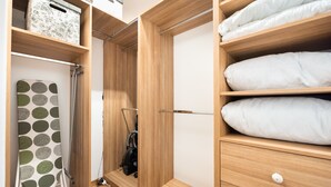 A walk-in closet with wooden shelves, a hanging garment rack, and a vacuum cleaner. - Daniszewska Cosy Apartment (Warszawa)