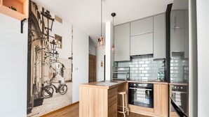 A modern kitchen with wooden cabinetry, a built-in island, and stainless steel appliances. - Daniszewska Cosy Apartment (Warszawa)