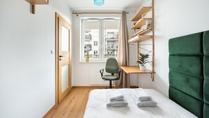 A compact bedroom with a bed, a desk, and a chair. - Daniszewska Cosy Apartment (Warszawa)