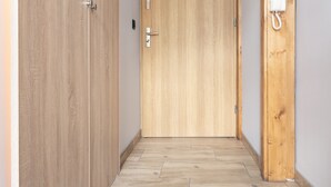 A hallway with wooden flooring and doors, one of which has a telephone mounted on it. - Piotrkowska Studio with Mezzanine (Lódz)