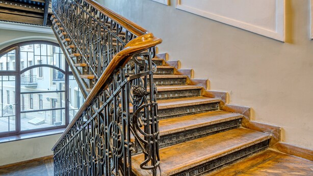 A grand staircase with ornate metal railings and wooden steps, leading to an upper floor. - Piotrkowska Studio with Mezzanine (Lódz)