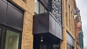 A building with a brick facade, large windows, and a black awning.