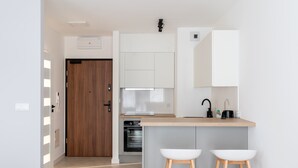 Eine moderne Küche mit Holztür, integrierten Geräten und weißen Barhocker.