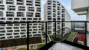 Ein modernes Mehrfamilienhaus mit mehreren Balkonen und Blick auf eine Grünfläche mit einem Spielplatz.