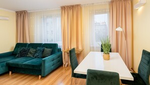 Una sala moderna con un sofá color turquesa, una mesa de comedor blanca y una silla verde.