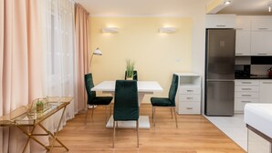 Una cocina moderna con un refrigerador de acero inoxidable, armarios blancos y un comedor con mesa blanca y sillas verdes.