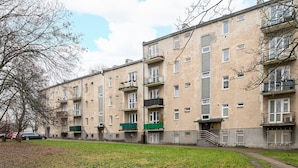 A multi-story residential building with balconies, a grassy courtyard, and a parked car. - Old Town Colourful Apartment (Warszawa)