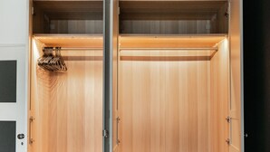 Un dormitorio con un armario de madera, una cama y una mesita de noche.