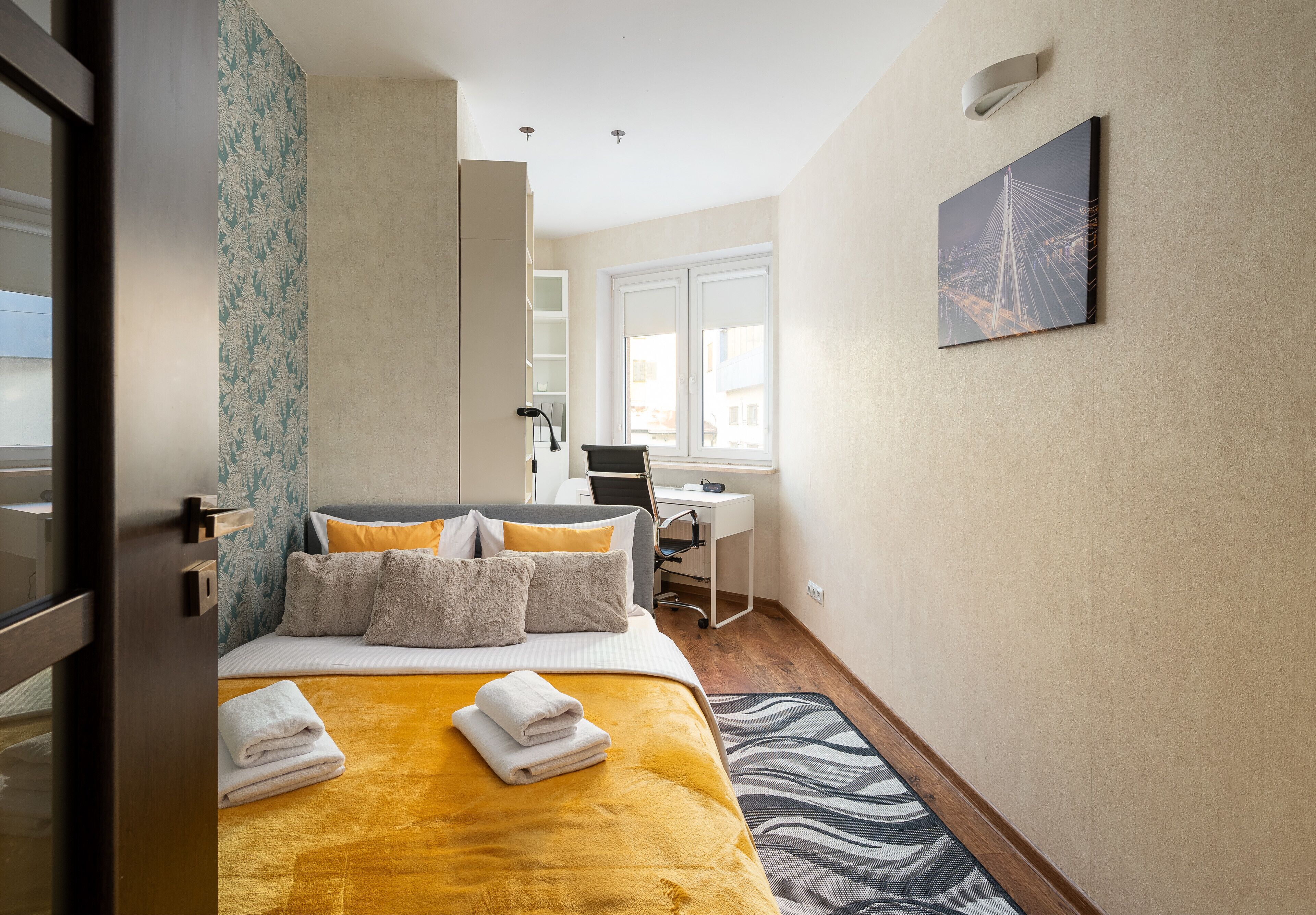 Ein Hotelzimmer mit Bett, Schreibtisch, Stuhl und Fenster.