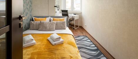 A hotel room with a bed, a desk, a chair, and a window.
