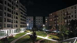 En nattbild av ett bostadskomplex med flera hyreshus, en central innergård med gångvägar och lite grönska.