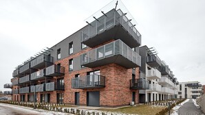 A modern multi-story building with a brick facade and large balconies. - Poznań Airport Comfy Apartment (Poznań)
