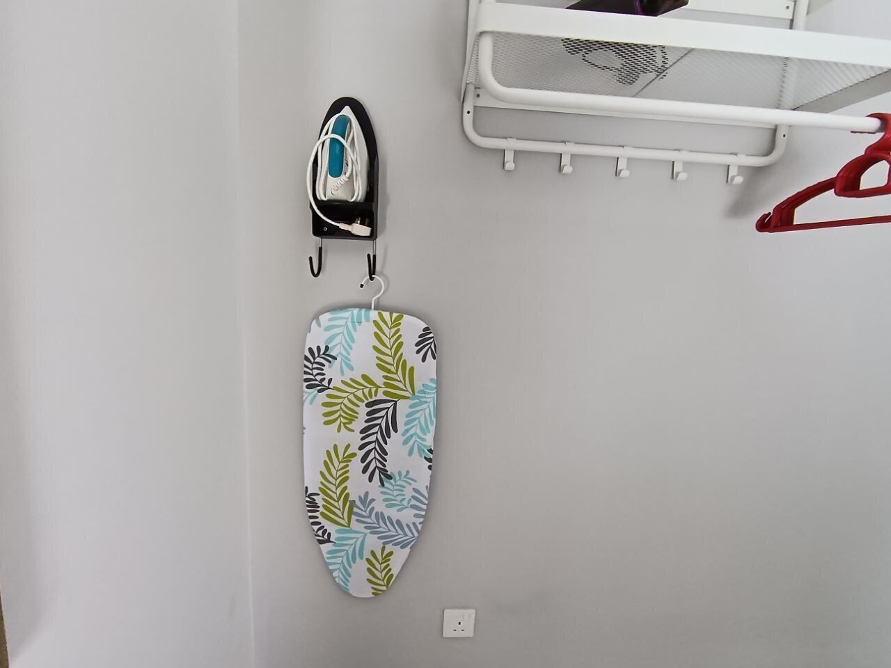 Una tabla de planchar fijada a la pared, con funda estampada de motivos florales.