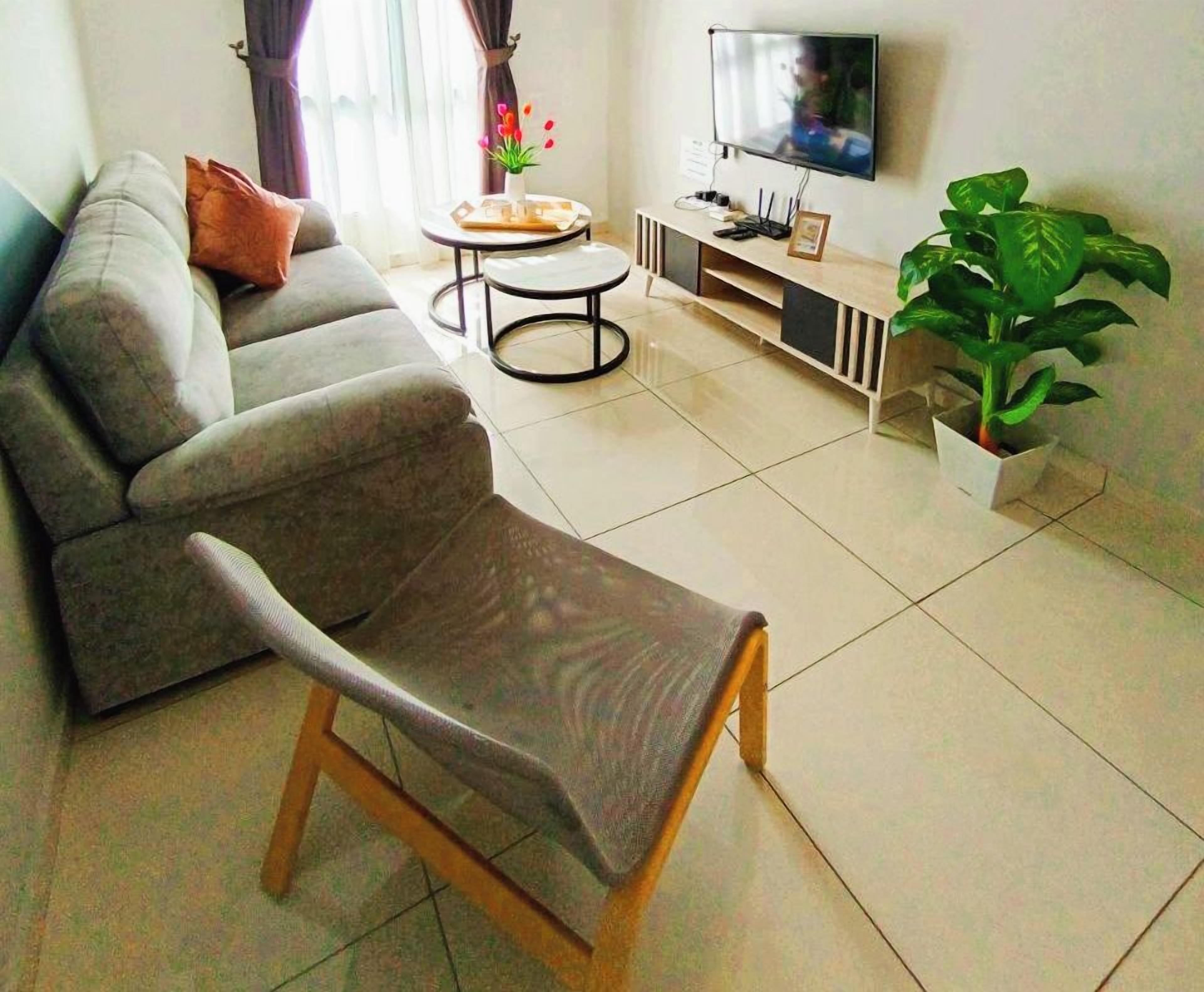 A modern living room with a sofa, a chair, a coffee table, a TV, and a ceiling fan. The text 'WIFI PROVIDED' is visible on the wall.